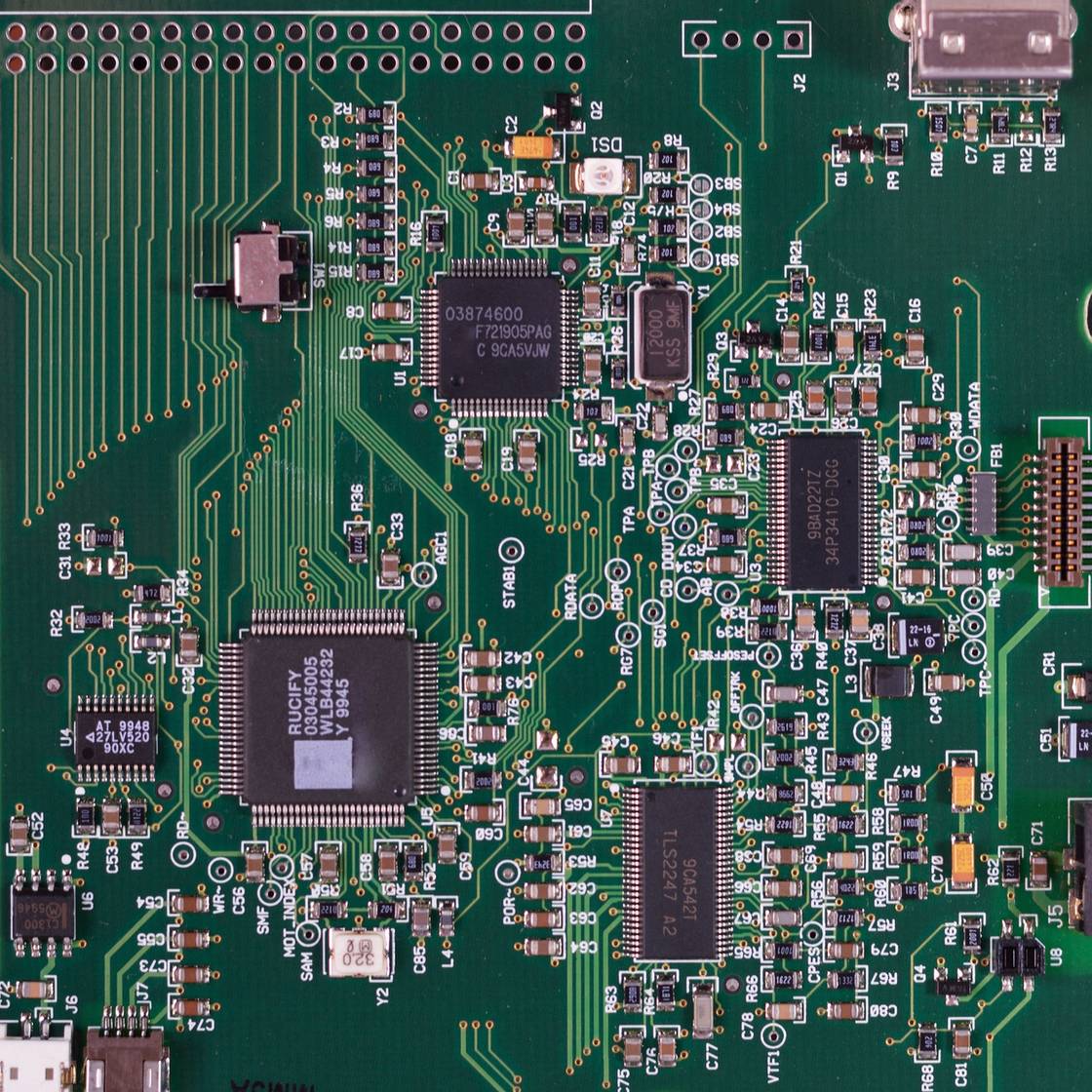 Close view of a printed circuit board surface, green circuit board featuring various components